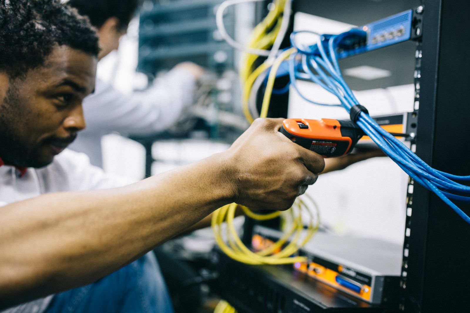 Engineer inspecting network cables and connections inside a server room
